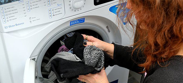 Woman carrying clothes to a tumble dryer  468437